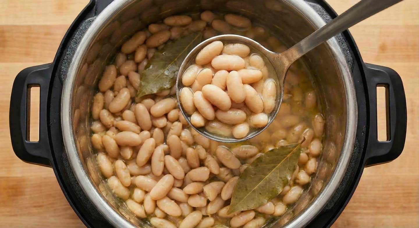 cannellini beans in an instant pot top down view of Instant Pot cannellini beans, with the Instant Pot visible below a ladle full of the cooked beans