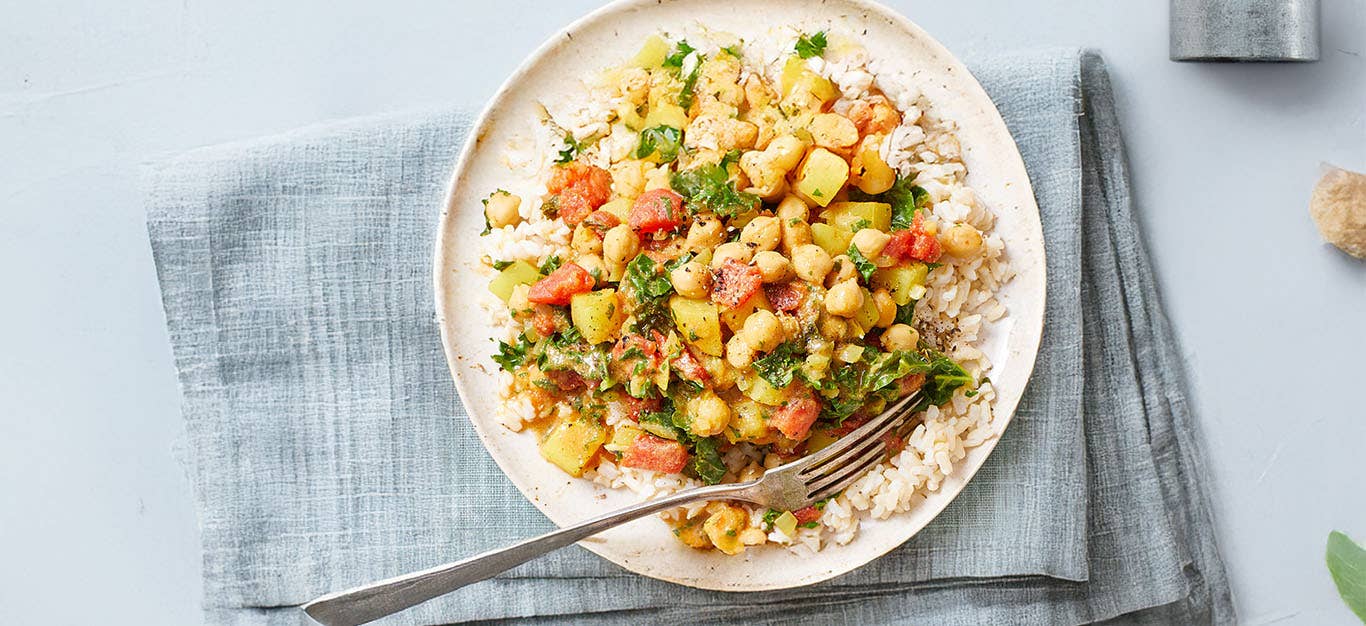 Chickpea Curry Stew with Kale on a white plate in a pale blue folded napkin