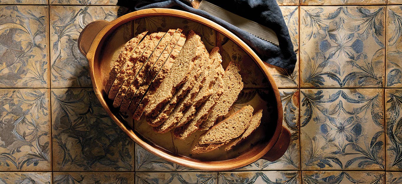 No-Knead Boule Bread in an oval dish on a rustic tiled background