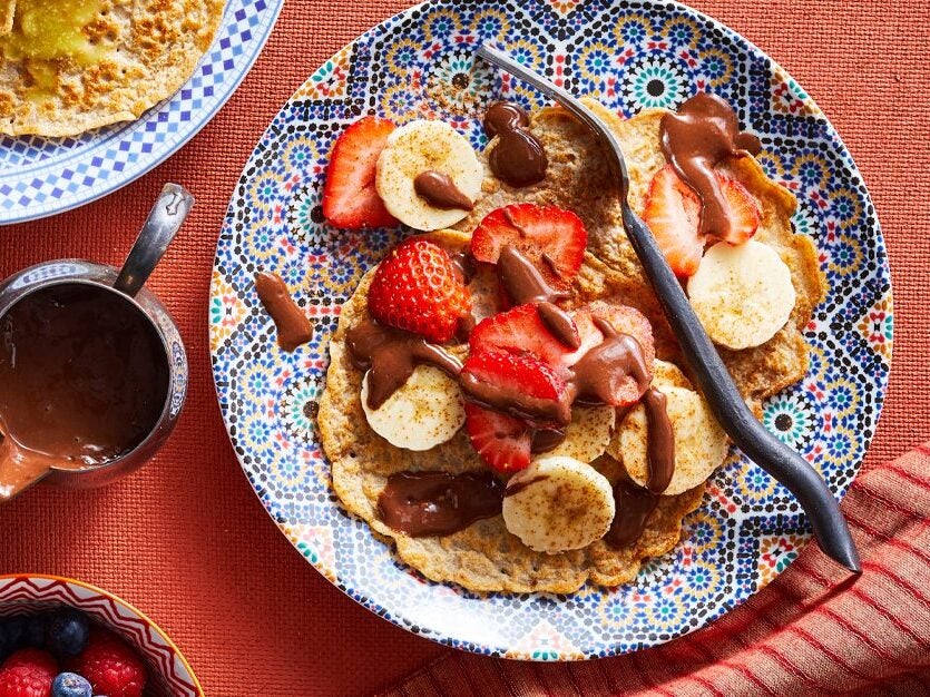 Sweet Moroccan Pancakes with Chocolate Banana Sauce and fresh fruit on a colorful plate and red tablecloth