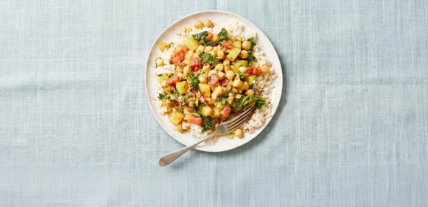 Chickpea Curry Stew with Kale on a white plate in a pale blue folded napkin