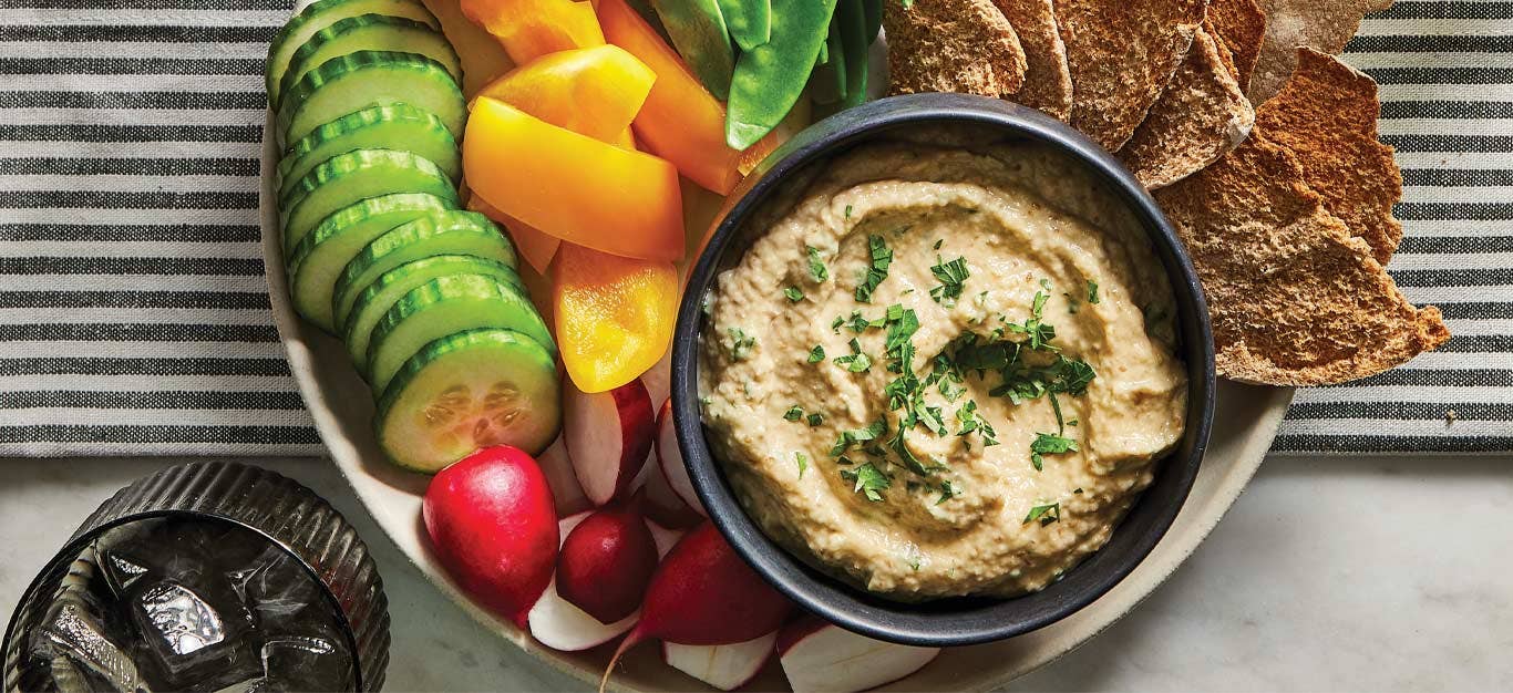 Oil-Free Baba Ghanoush in a small gray bowl surrounded by fresh veggies and crackers