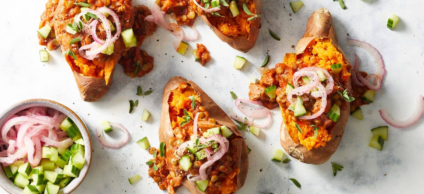 Barbecue Stuffed Sweet Potatoes with onion and cucumbers on a white countertop