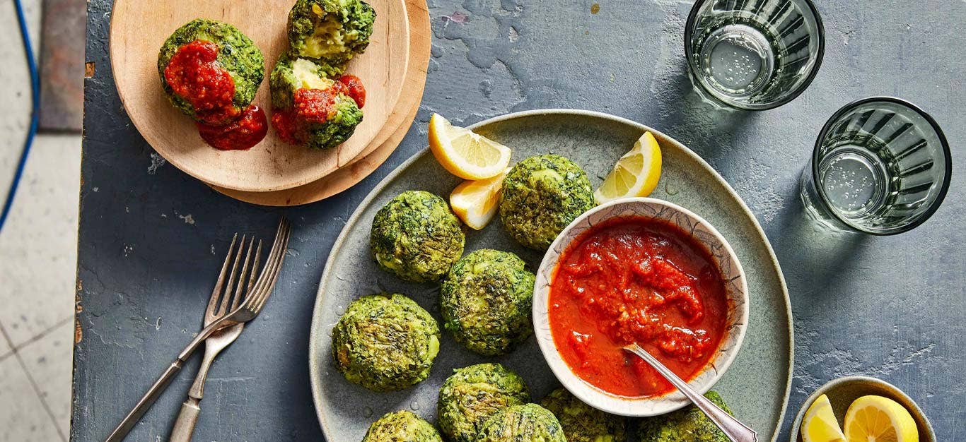 Cheesy Vegan Stuffed Spinach Bites on a gray plate with a small bowl of marinara sauce for dipping
