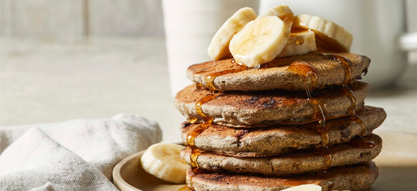 Gluten-Free Chocolate Chip Pancakes drizzled with maple syrup and banana slices