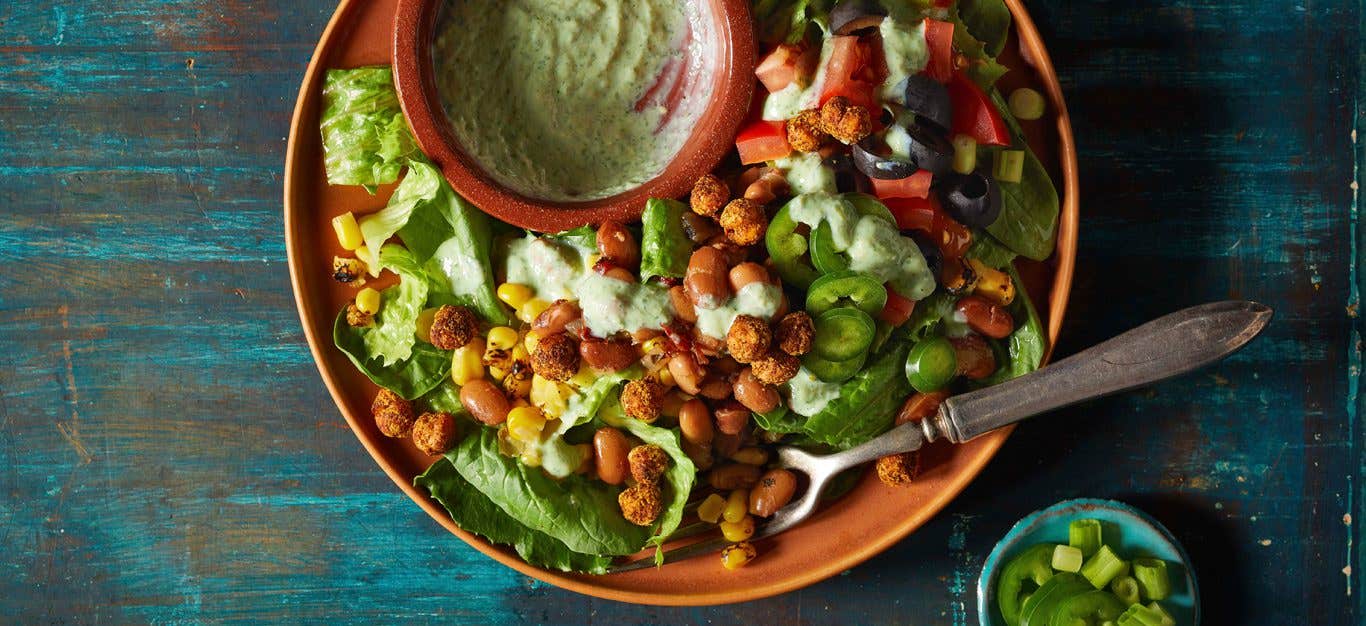 Cilantro Ranch Bean Salad in an orange bowl on a wooden tabletop