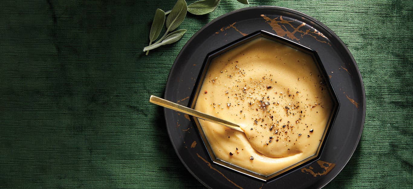 Savory Chickpea Flour Gravy in a black hexagonal bowl with a metal spoon against a green velvet background