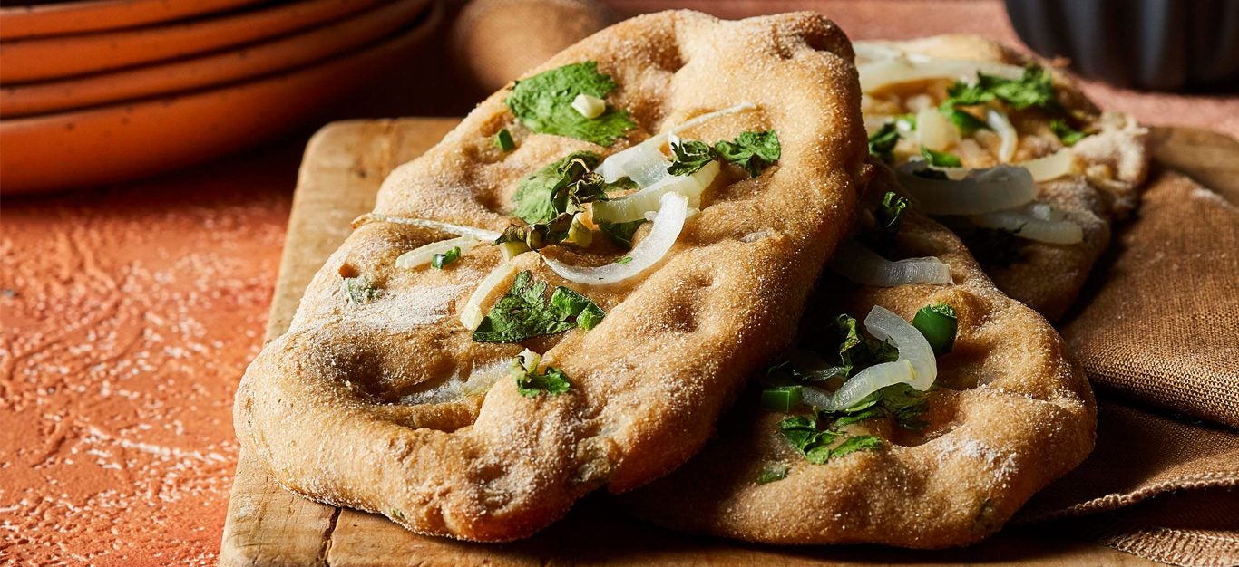 Garlic-Jalapeño Naan with fresh cilantro on a wooden cutting board