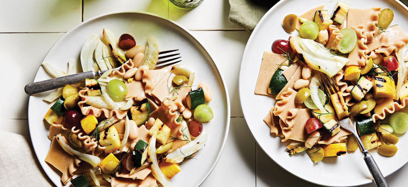 Grilled Summer Squash Pasta Salad on white plates with metal forks on top of white tile