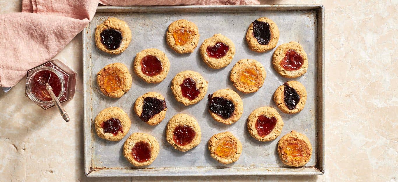 Jam Dot Holiday Cookies - Photo taken from above of a baking sheet full of finished cookies with jam dots in the center