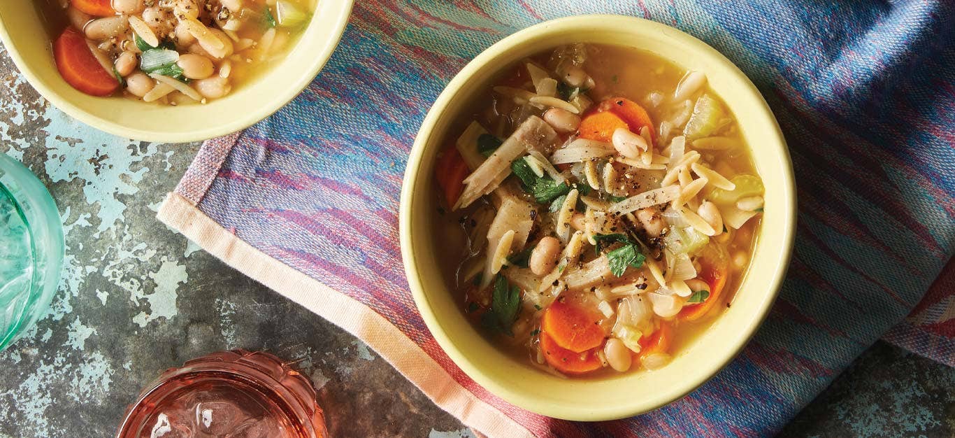 Lemon Orzo Soup with Jackfruit in yellow bowls against a colorful cloth napkin