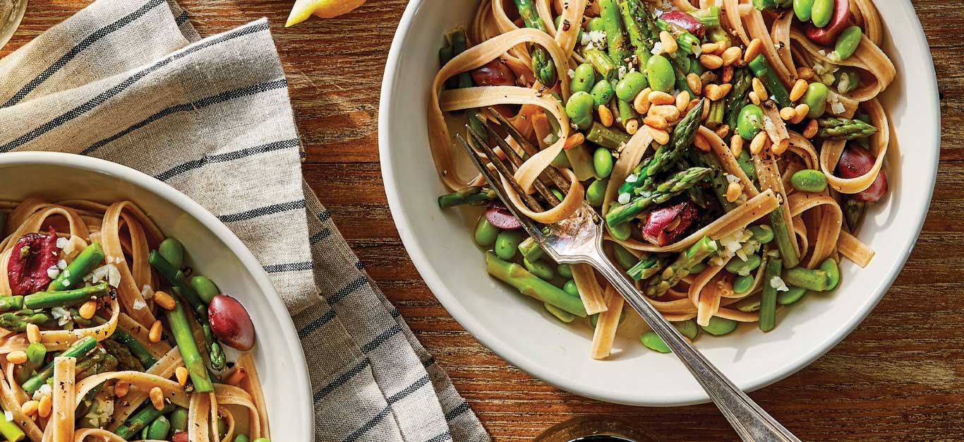 Lemony Asparagus Fettuccine in white bowls with metal forks against a wood tabletop