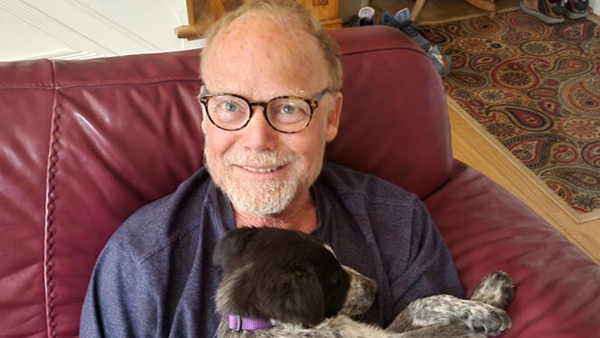 A photo of Michael Andrus, who went plant-based after a cancer diagnosis, holding his dog and smiling