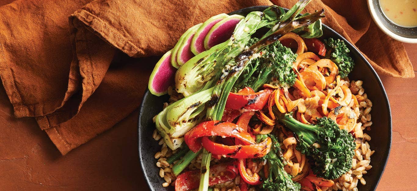 Miso-Ginger Grilled Vegetable Farro Bowls against an orange backdrop with orange cloth napkins