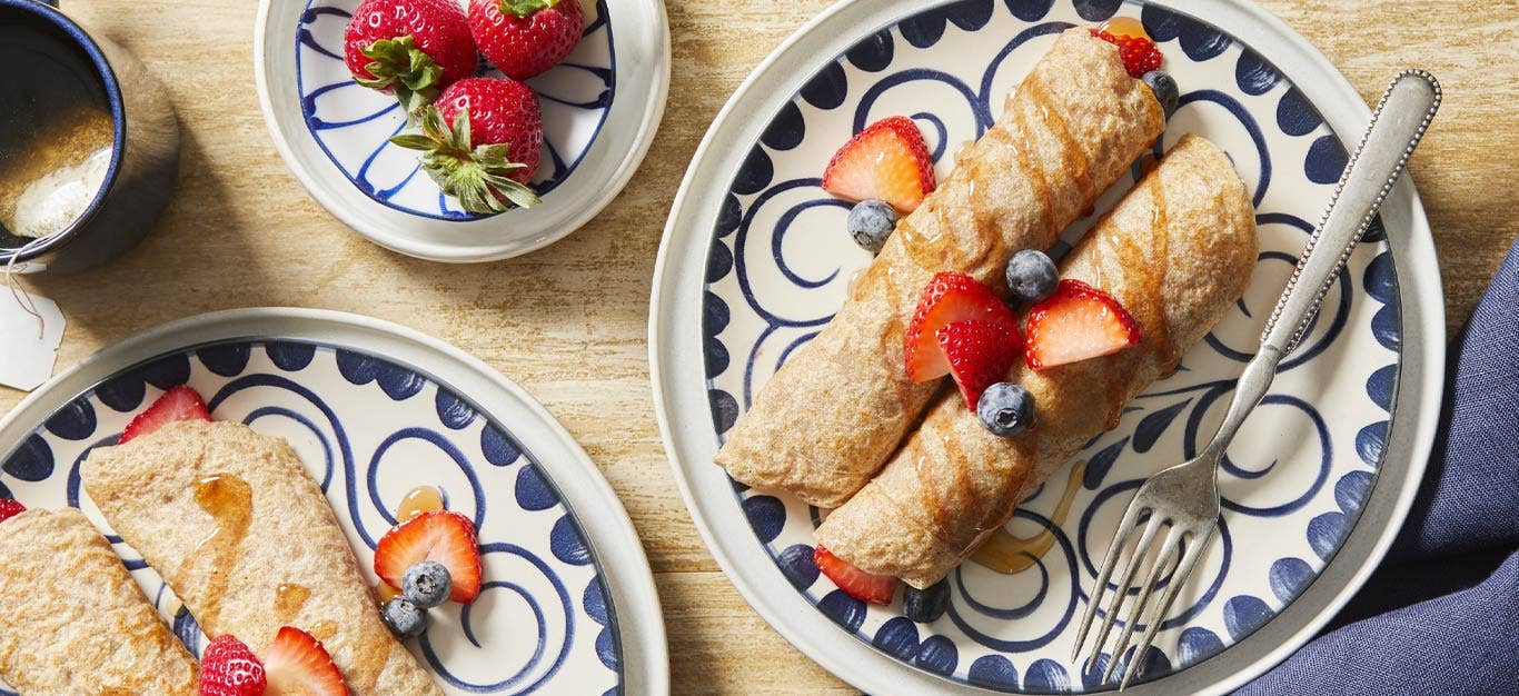 Vegan Palacinky (Czech Sweet Crepes) on blue and white china plates topped with fresh berries