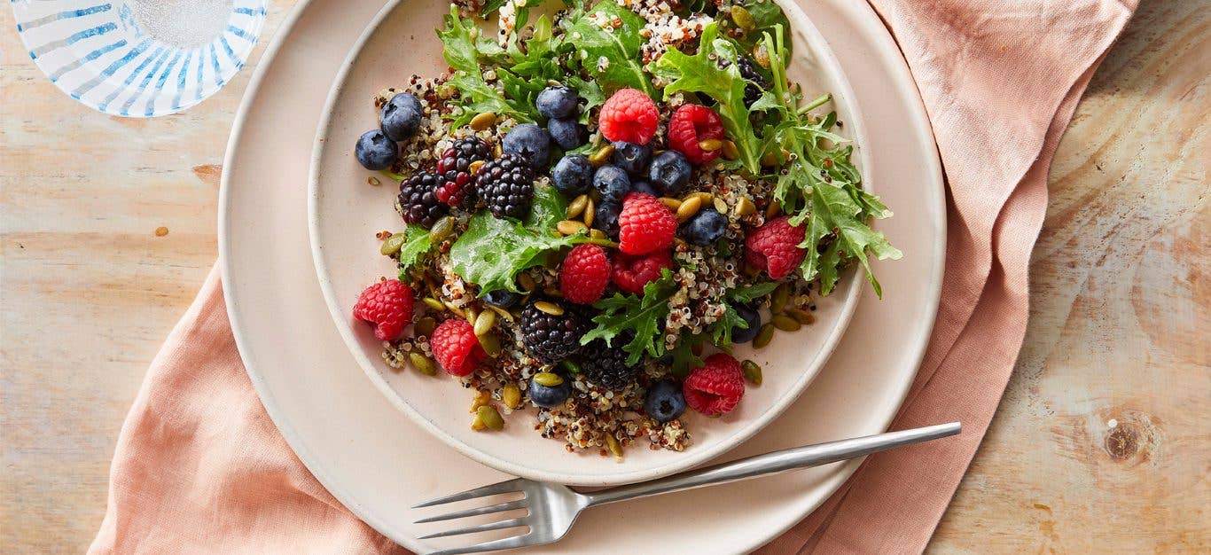 Power Berry Quinoa and Kale Salad on a white plate with a metal fork