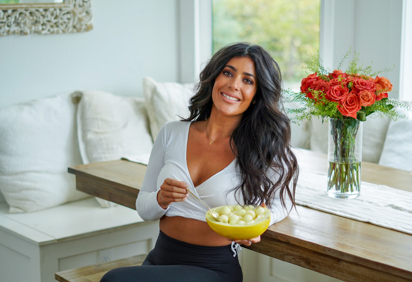 Cookbook author Kiki Nelson of plantifully lean sits in her home eating balled melon