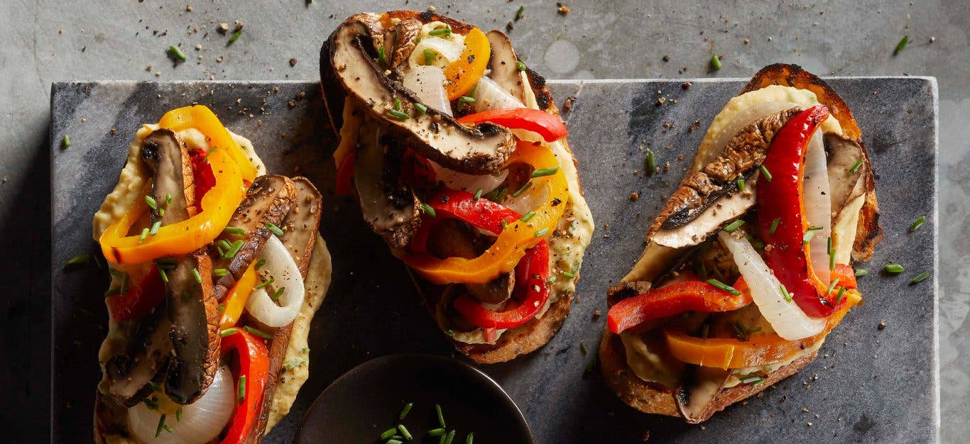 Shredded Portobello Mushroom Sandwiches with peppers and onions on a gray slate serving board
