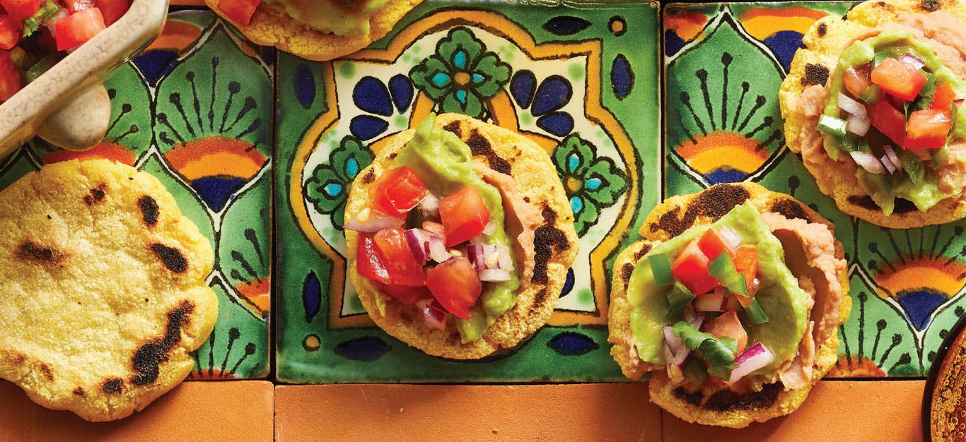 Homemade Vegan Sopes with Spicy Refried Beans on orange and green Mexican tiles