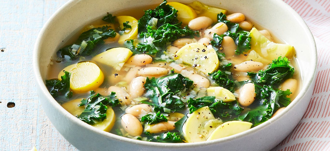 Summer Squash Soup with White Beans and Kale in a white bowl