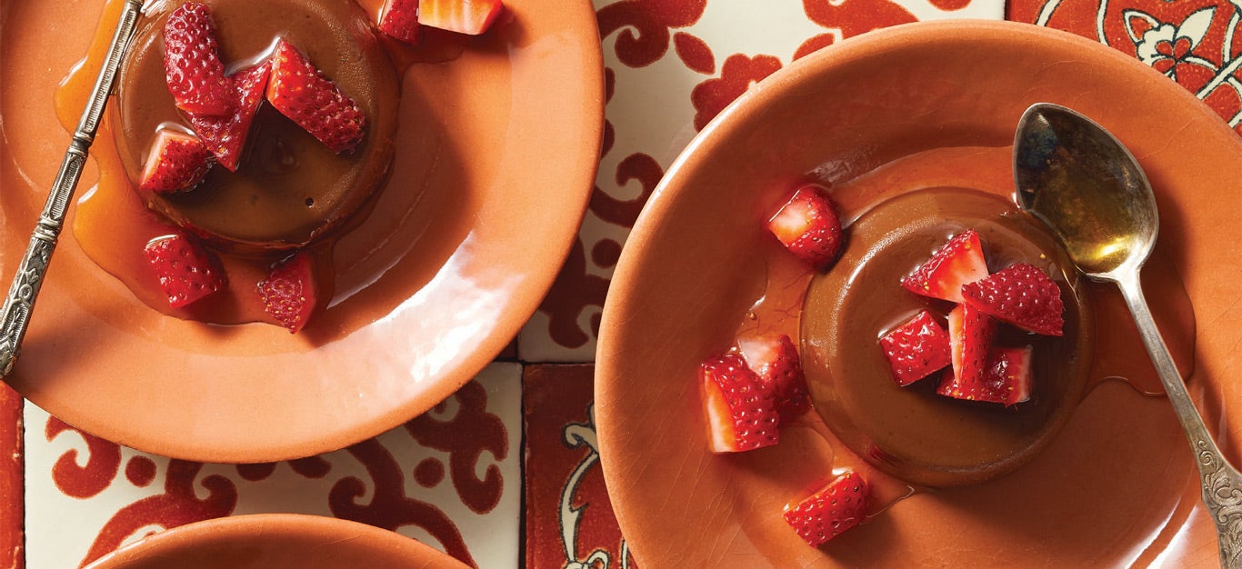 Chocolate Vegan Flan topped with strawberries on orange plates