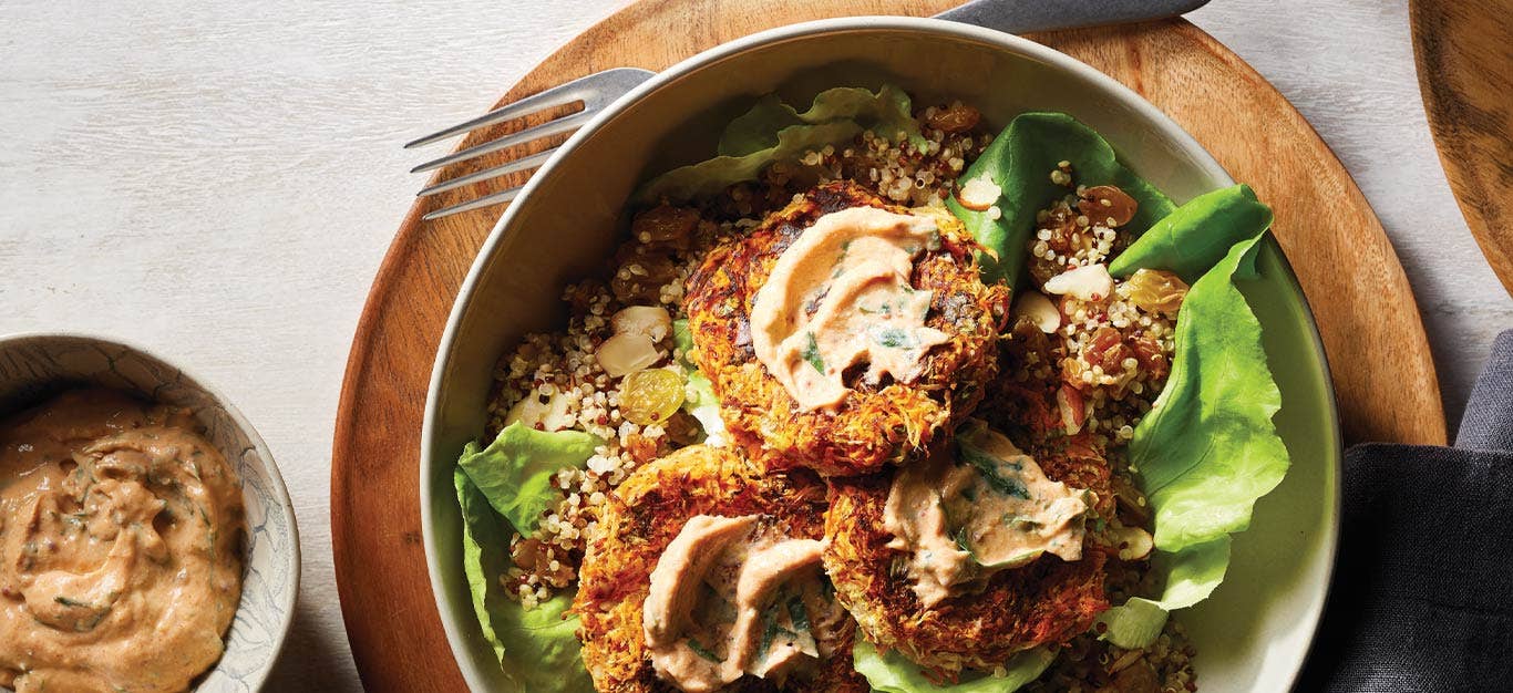 Turnip and Sweet Potato Croquettes with Quinoa Pilaf and Tofu Remoulade in a white bowl on a wooden plate next to a small bowl of the remoulade