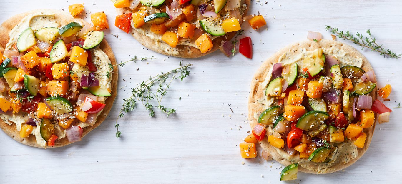 Vegetable Pitas with Everything Spice Hummus on a white table with fresh thyme sprigs