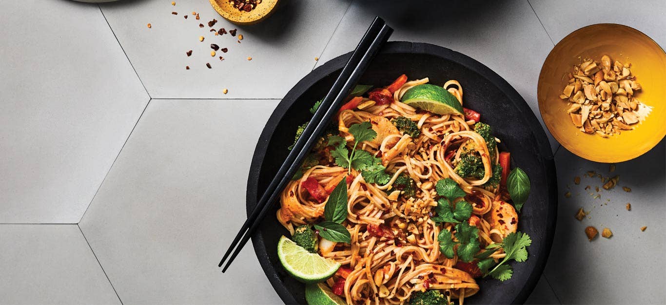 Thai Red Curry Noodles with Mixed Veggies in a black bowl with black chopsticks