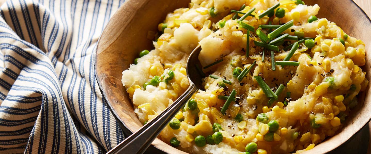 A wooden serving bowl of Yuca Mash with Corn and Peas