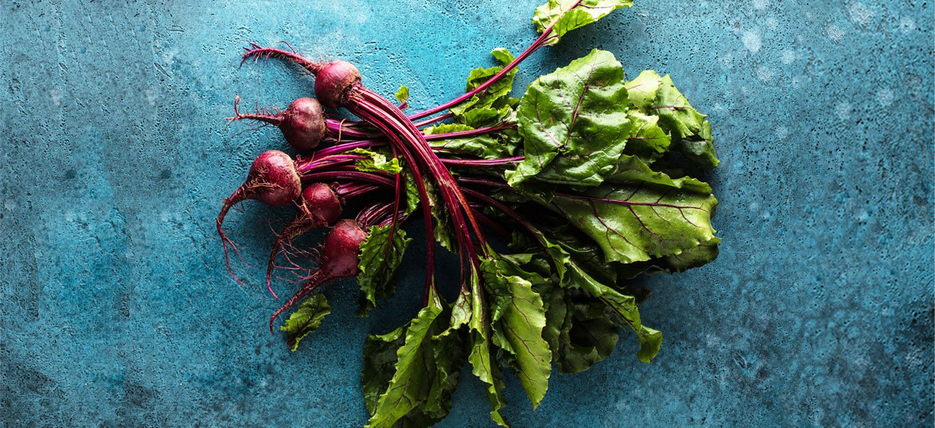 Raw beets on blue background