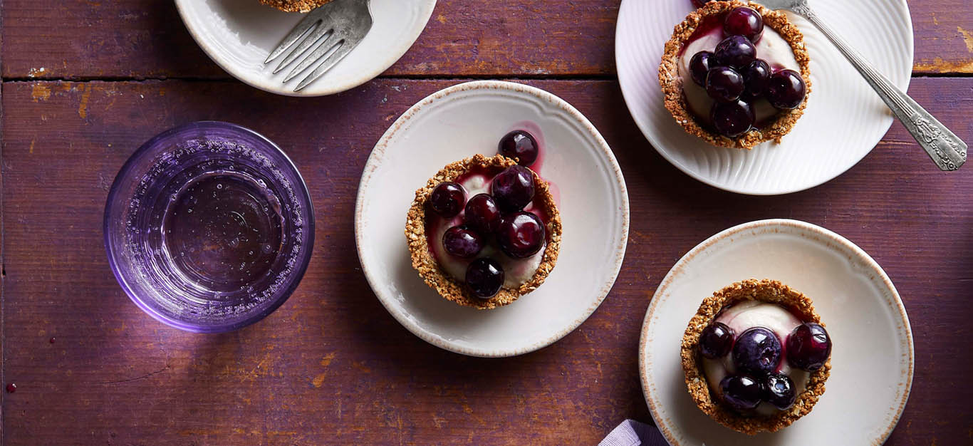 Mini tarts shown on individual plates - small tartlets with a lavender-vanilla filling and saucy blueberry topping