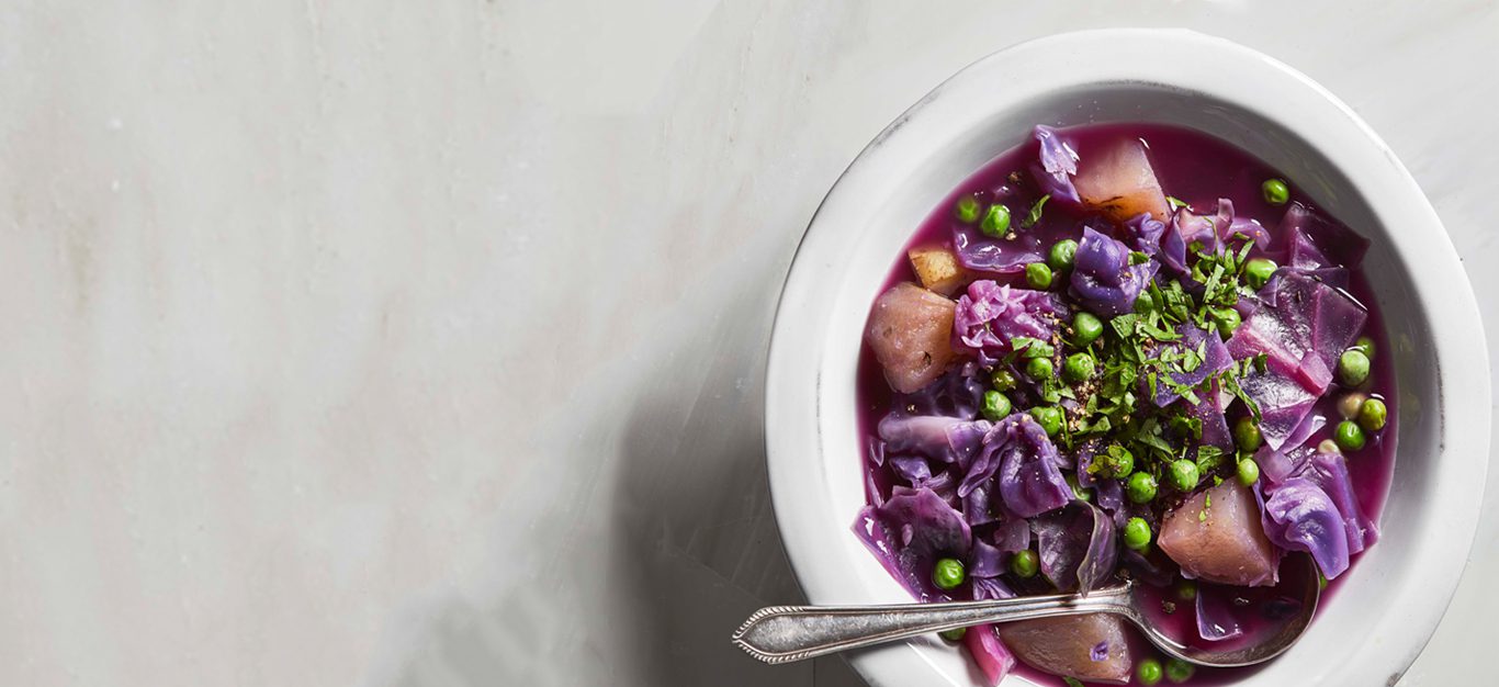Hearty Purple Cabbage Soup in a white bowl with metal spoon