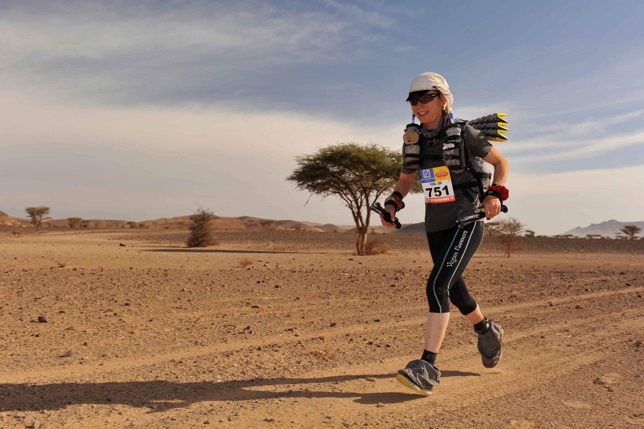 Vegan ultramarathon runner Fiona Oakes runs across the Sahara desert, smiling
