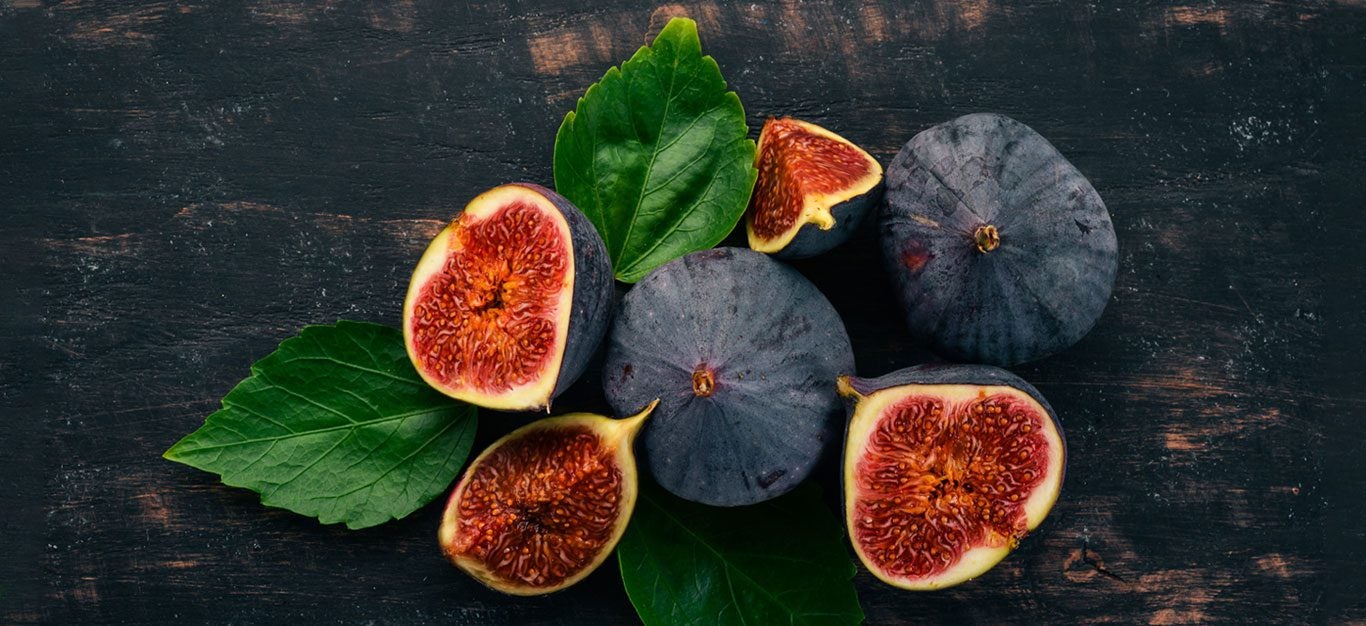 Figs - whole and cut with some leaves on black background