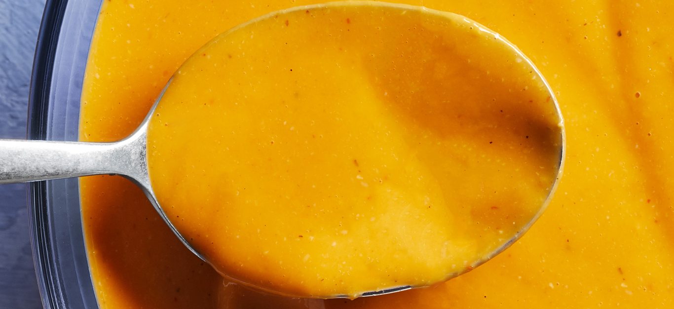 vegan queso sauce - up close photo of spoon full of orange creamy cheesy vegan queso sauce