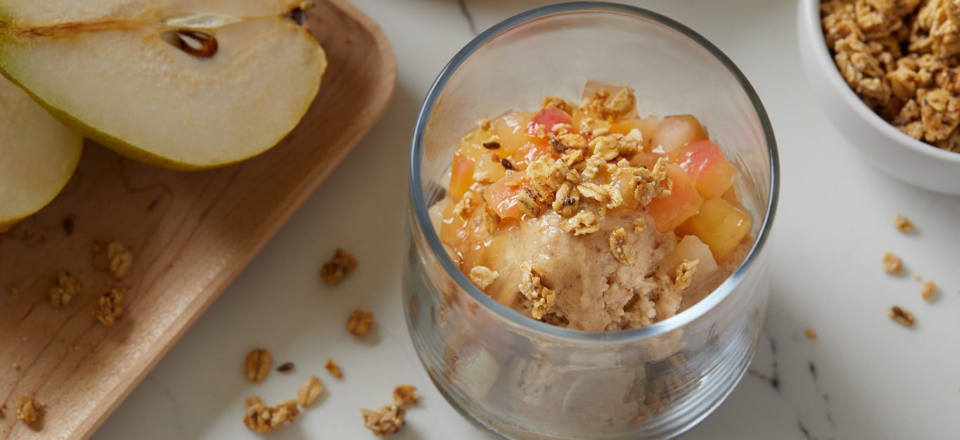 cinnamon banana nice cream - fruity, dairy-free ice cream shown in a glass cup topped with chopped, cooked-down pears