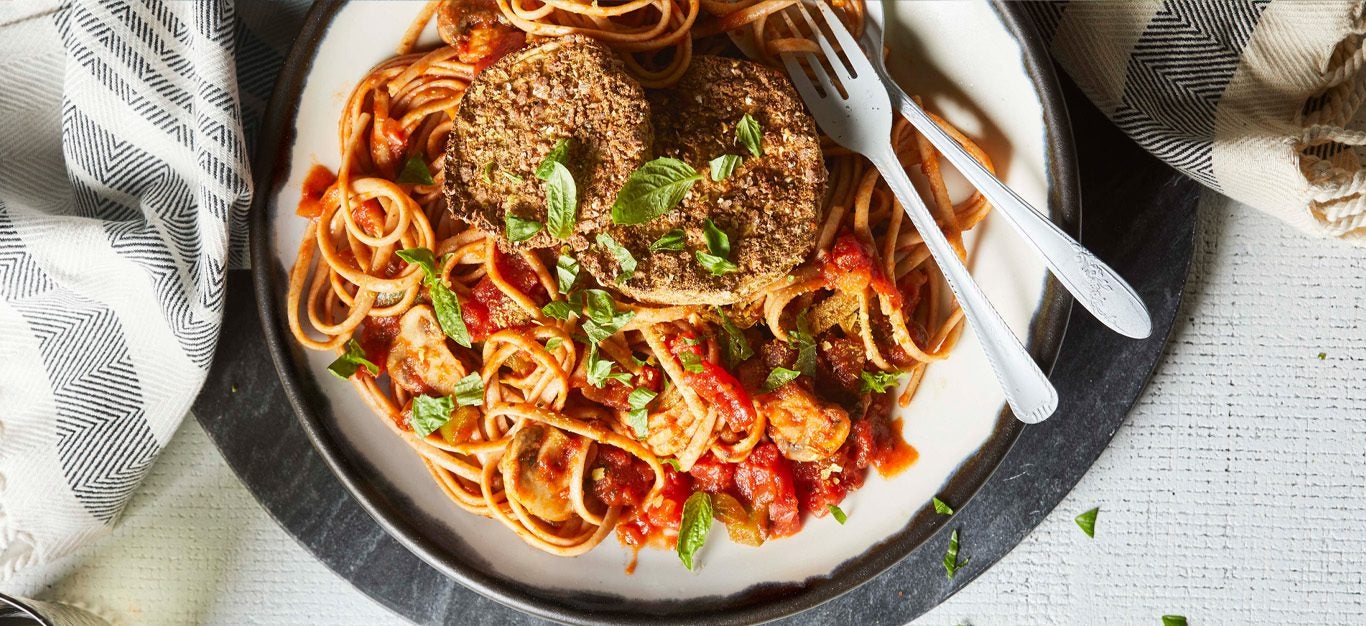 air-fryer eggplant parmezzan - breaded and fried slices of eggplant atop a spaghetti dish with marinara sauce