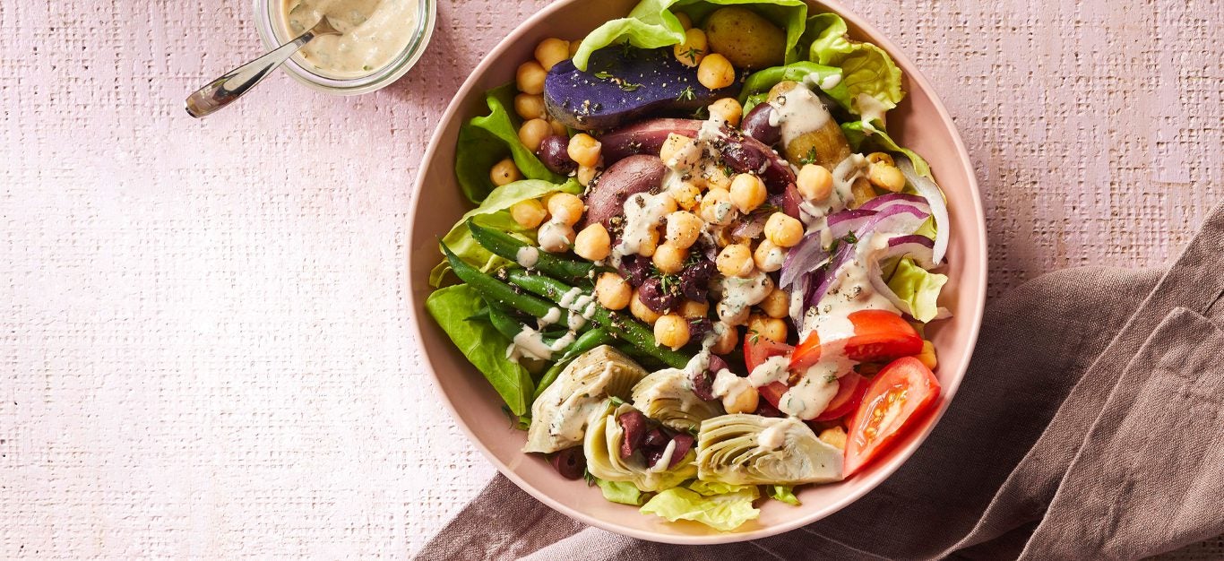 Vegan Niçoise Salad Bowls in a light pink dish with a small bowl of tahini dressing