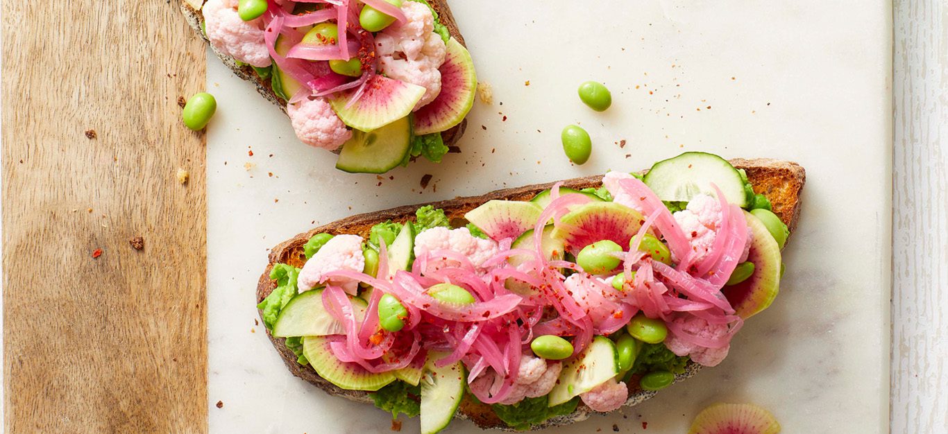 Lemony Spring Pea Toasts with watermelon radishes on a wood cutting board