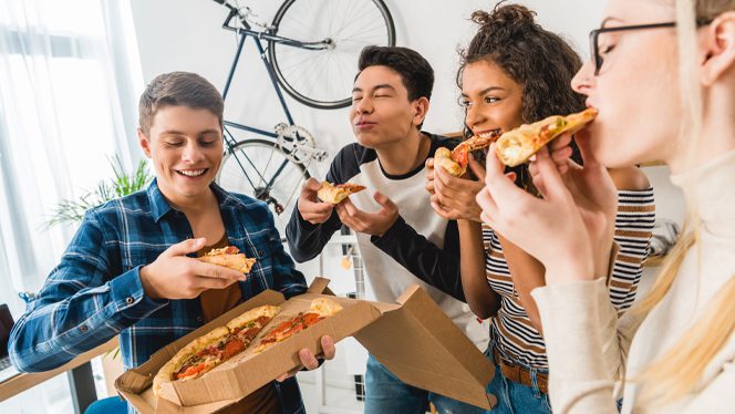 Teenagers gather in a circle and eat pizza