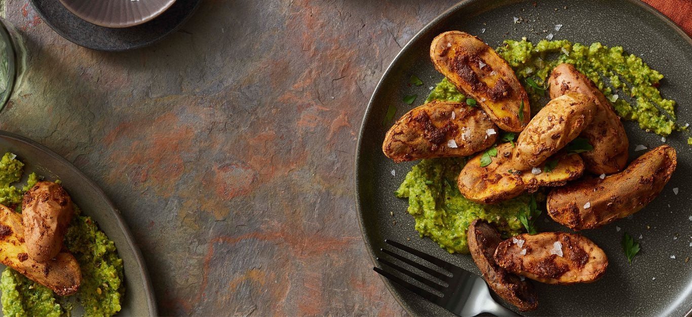 Air-Fried Fingerling Potatoes with a green sauce on a black plate