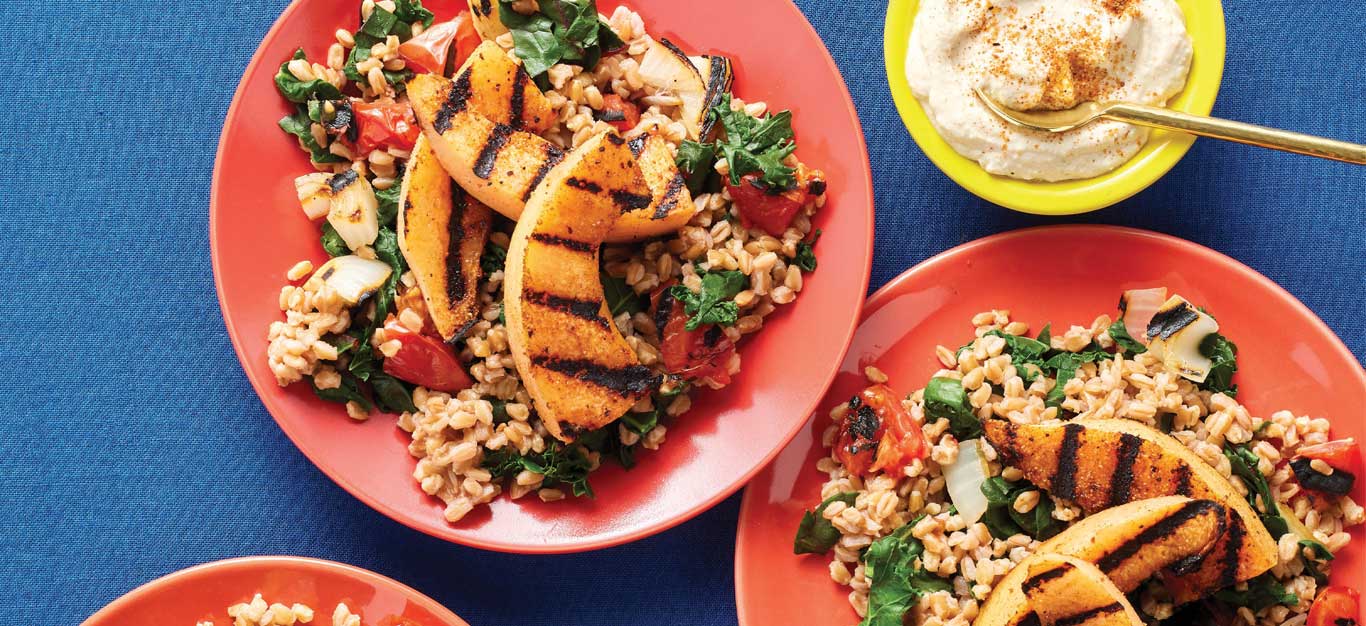 Farro Pilaf with Veggies and Blackened Melon on pink plates against a blue tabletop