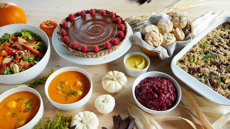 Vegan Thanksgiving table spread featuring chocolate raspberry pie, butternut squash soup, and a cheesy bean and rice casserole
