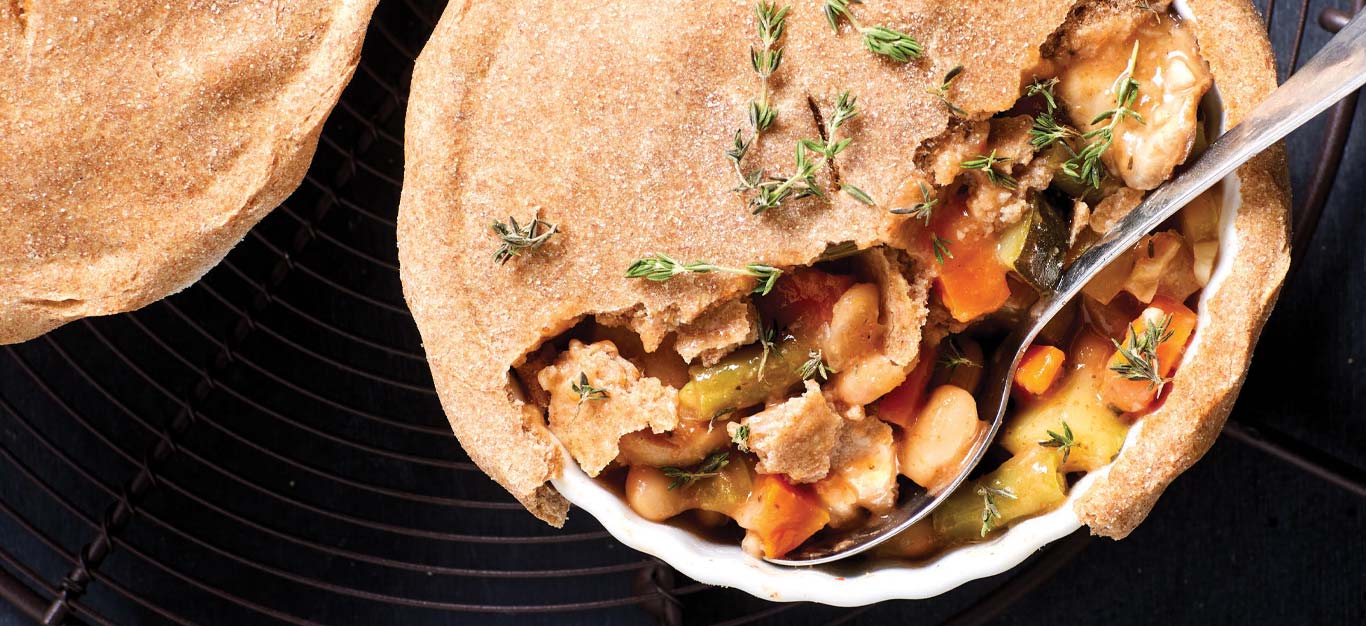 Mini Tuscan Bean Vegan Pot Pies in a white ceramic dish with a metal spoon