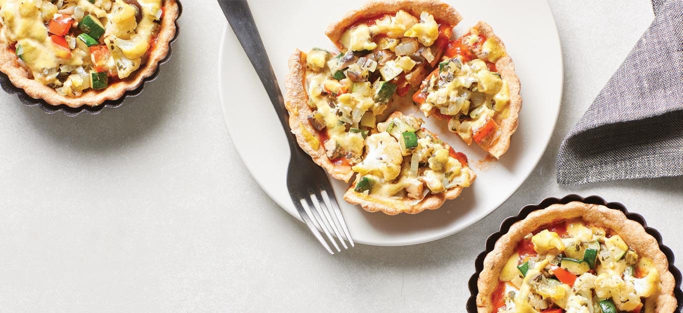 Mini Deep-Dish Pizza Pies in pie tins with one pie on a white plate