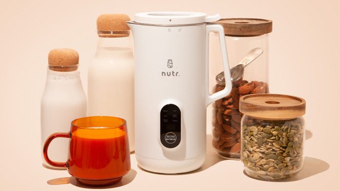 Nutr machine next to glass jars of nut milk and jars of whole nuts