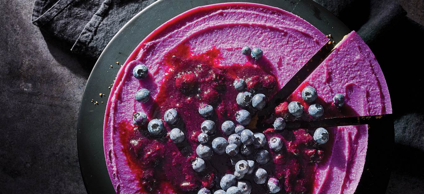The Great Purple Sweet Potato Pie topped with fresh blueberries on a gray cake platter