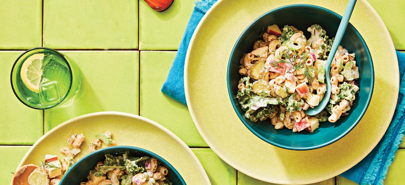 Dilly Vegan Macaroni Salad in a blue bowl on a yellow plate against a green tile background