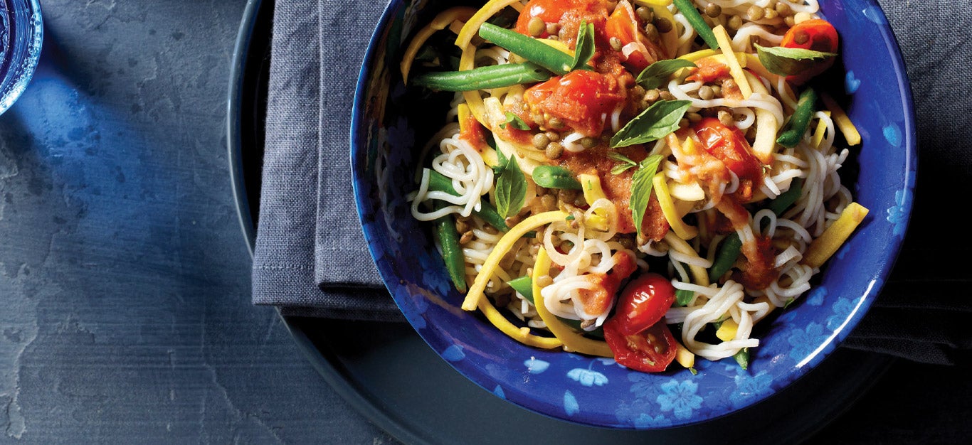 Tofu Shirataki Noodles with Lentils, Green Beans, and Tomatoes in a dark blue bowl