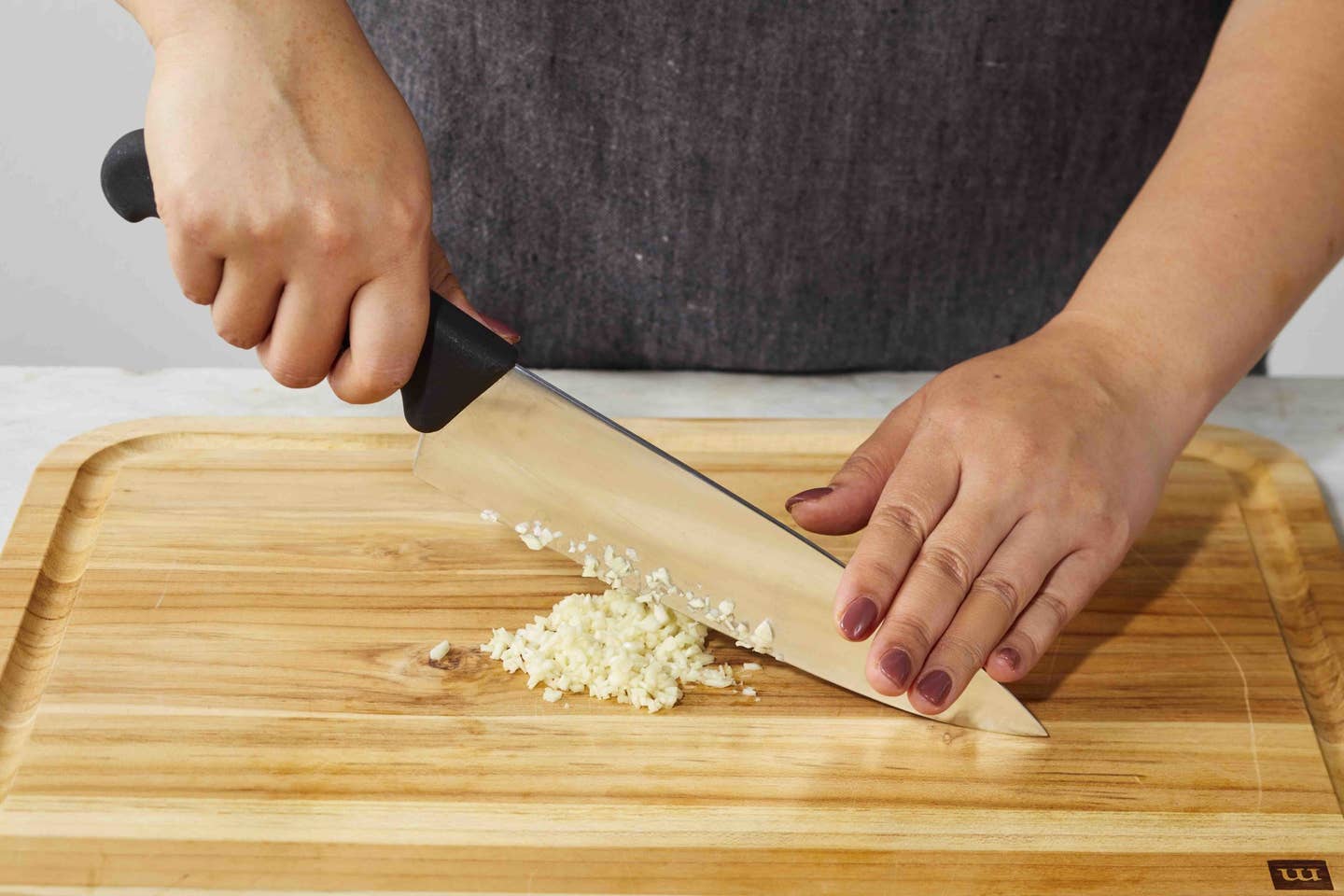 A chef minces garlic on a cutting board